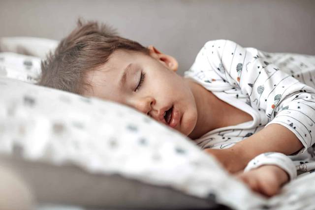 Petit garçon endormi dans un lit.