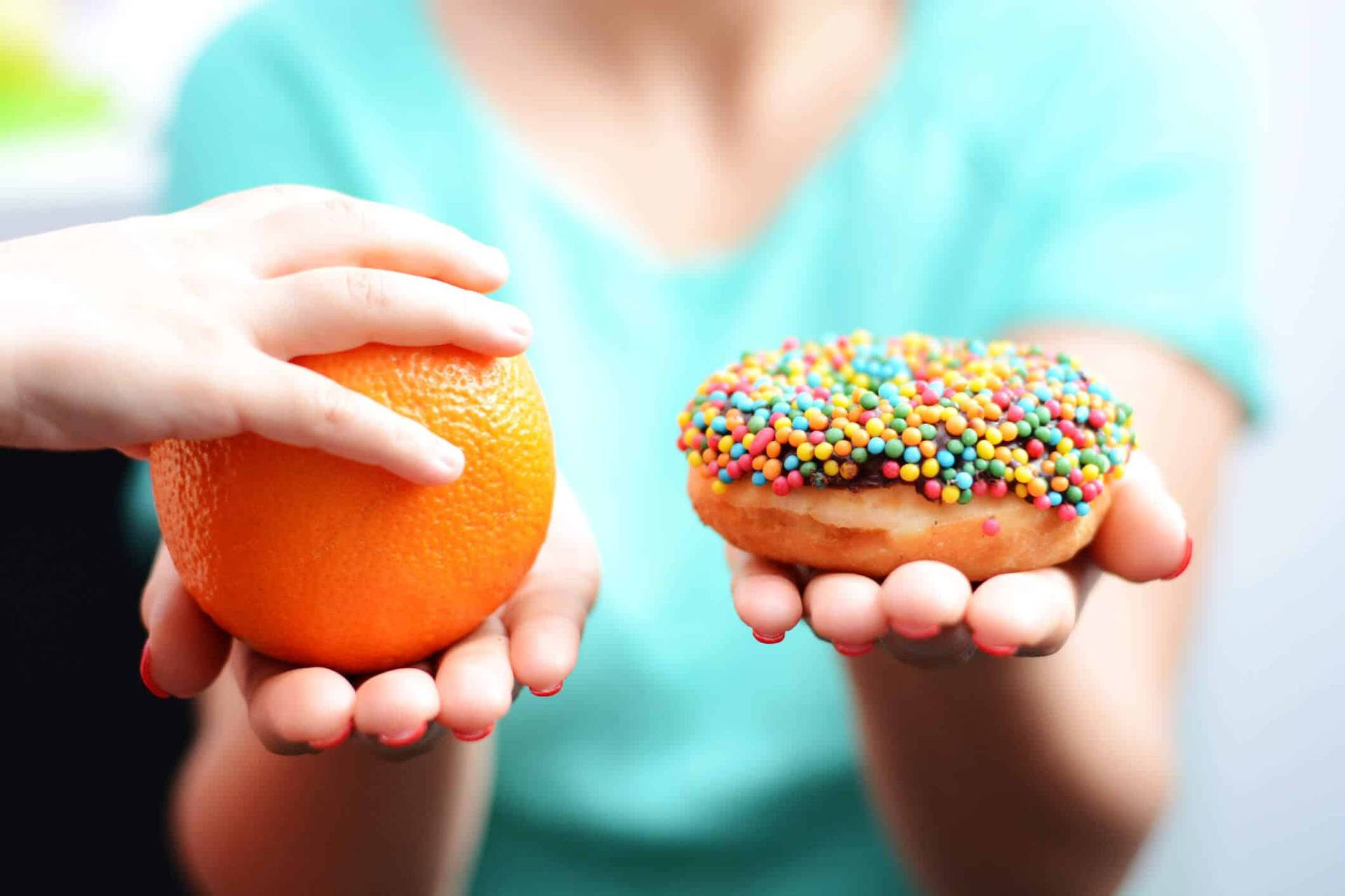 Personne choisissant entre une orange et un beignet.