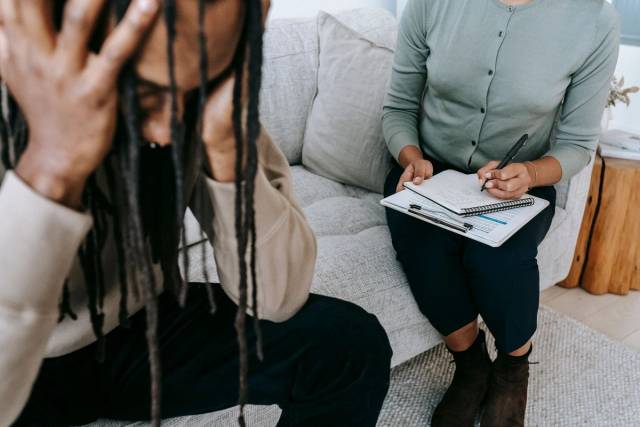 Une séance de thérapie montrant un patient inquiet et un thérapeute prenant des notes