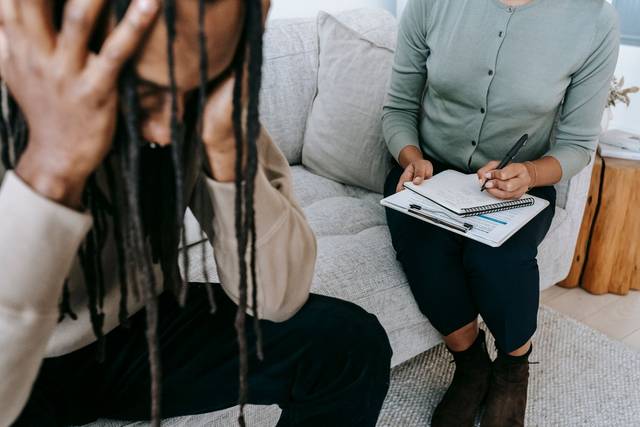Une séance de thérapie montrant un patient inquiet et un thérapeute prenant des notes