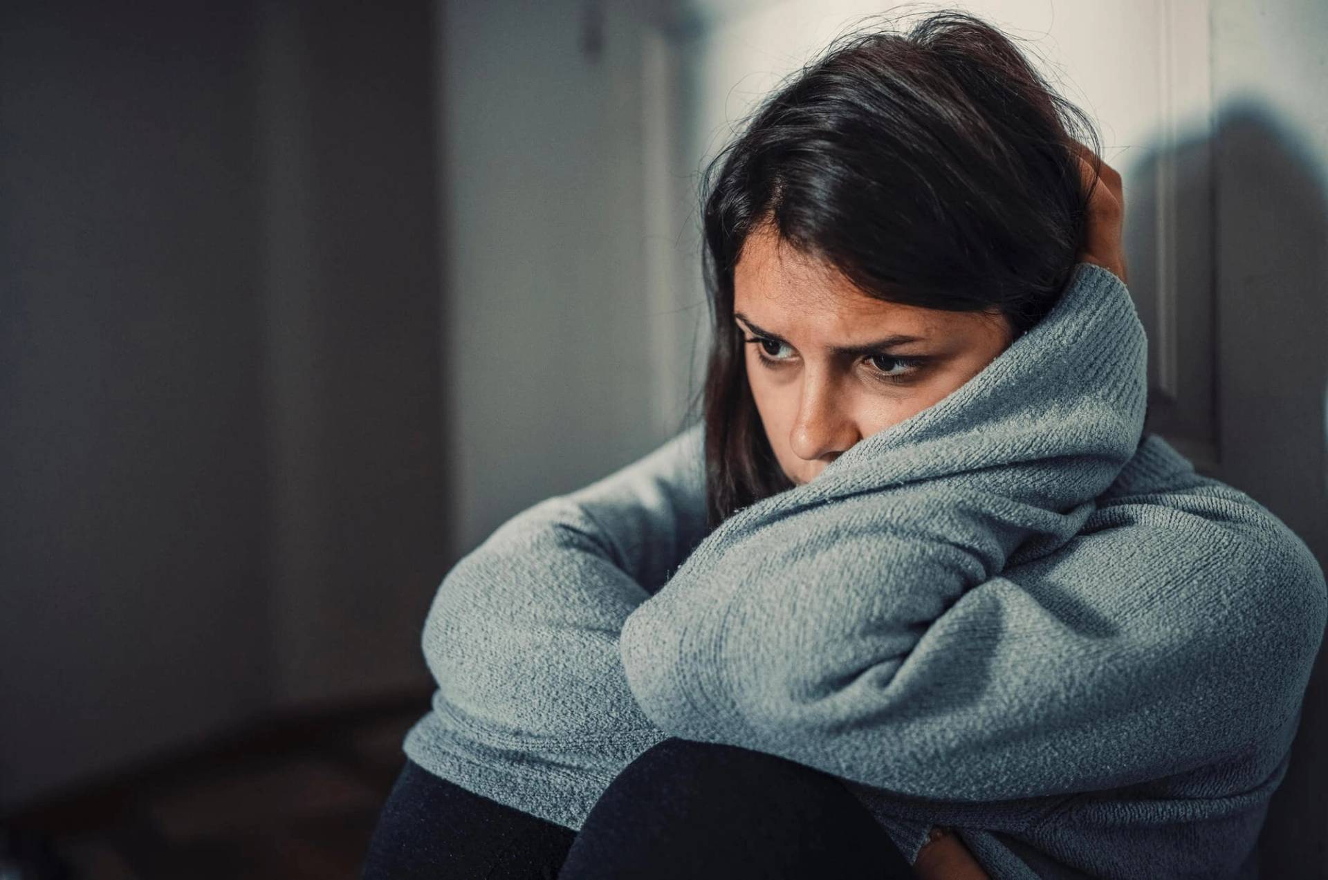 Femme recroquevillée et enveloppée dans une couverture.