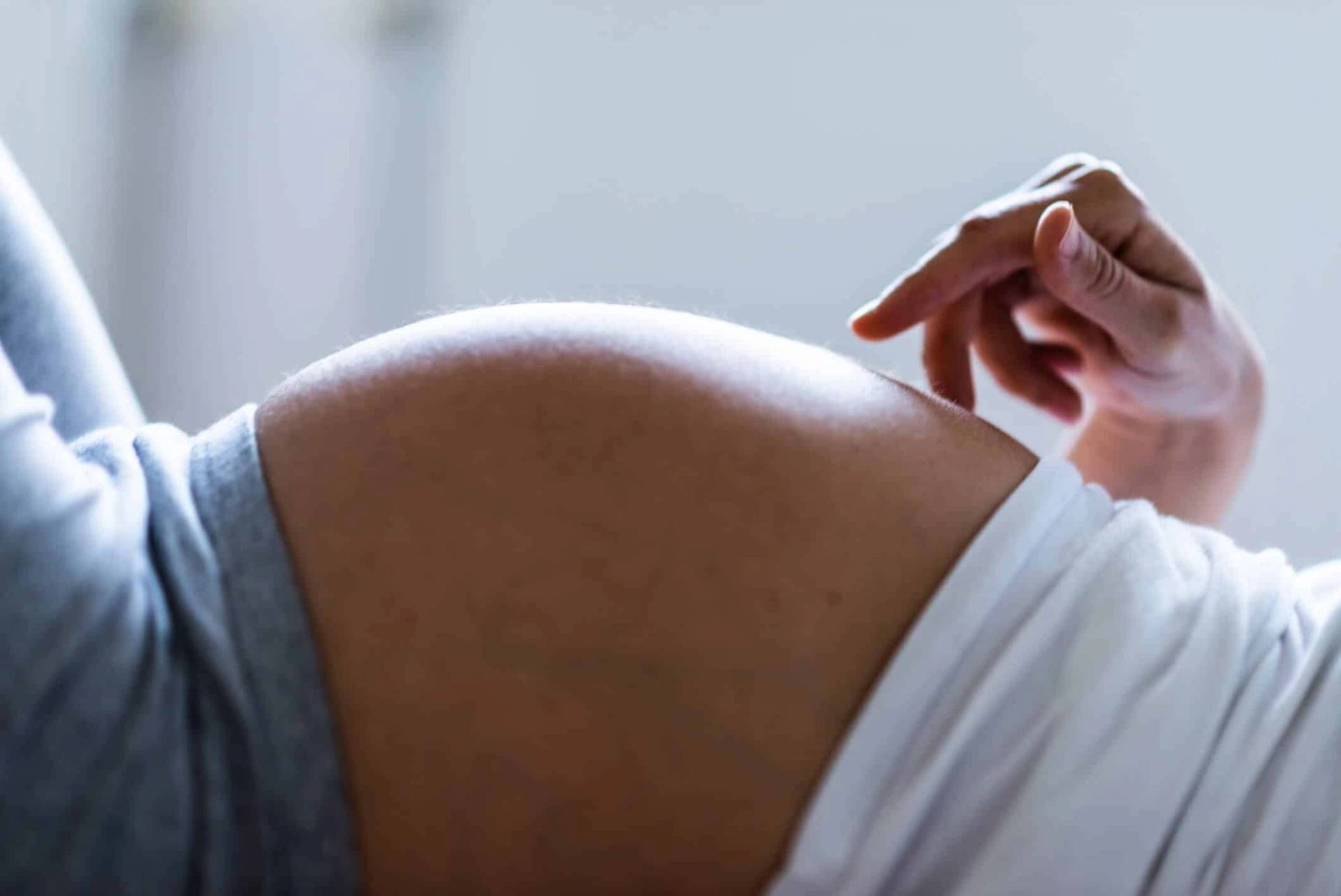 Gros plan sur le ventre d’une femme enceinte allongée.