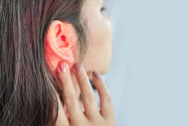 Femme touchant son oreille, avec un halo rouge ajouté sur celle-ci.