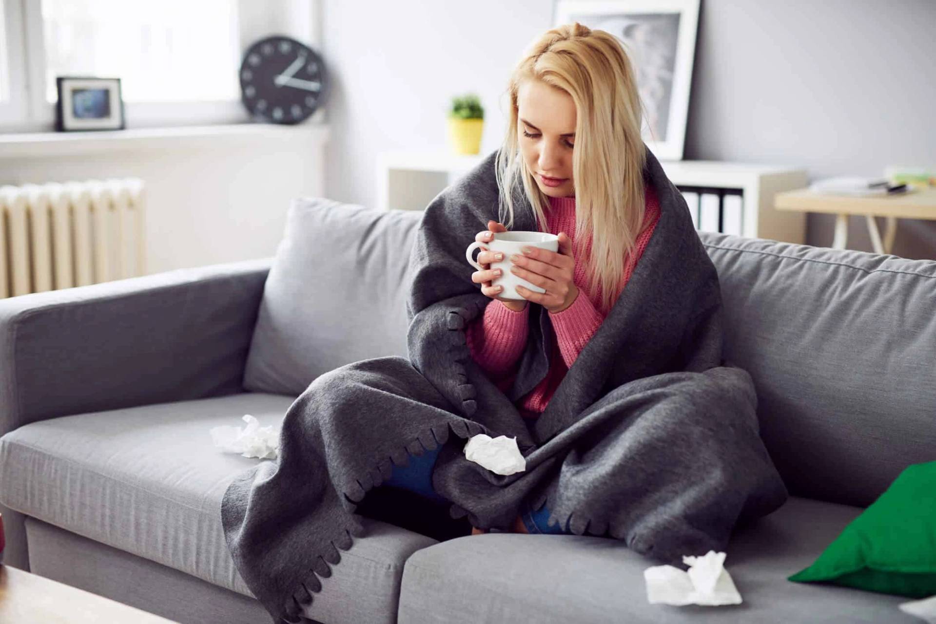 Femme enveloppée dans une couverture tenant une tasse.