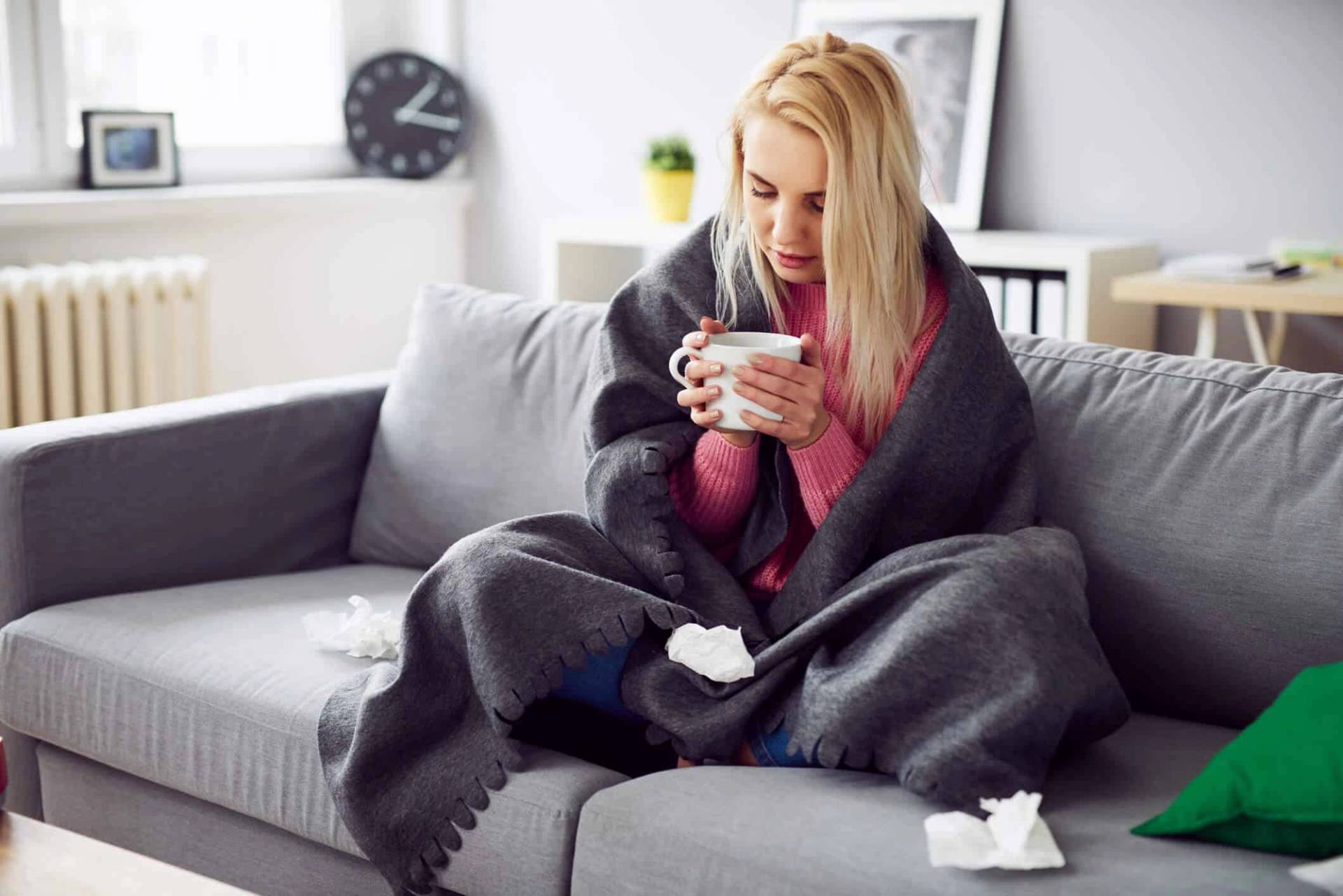 Femme enveloppée dans une couverture tenant une tasse.