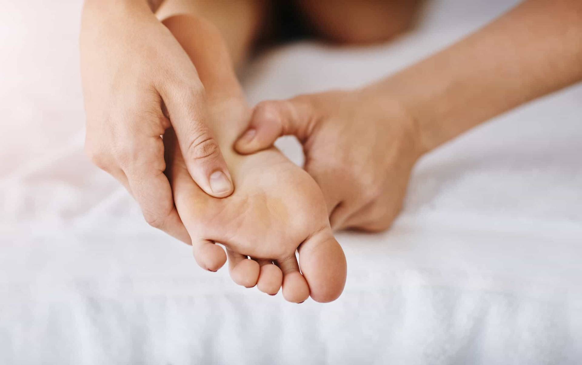Mains massant la plante d’un pied.