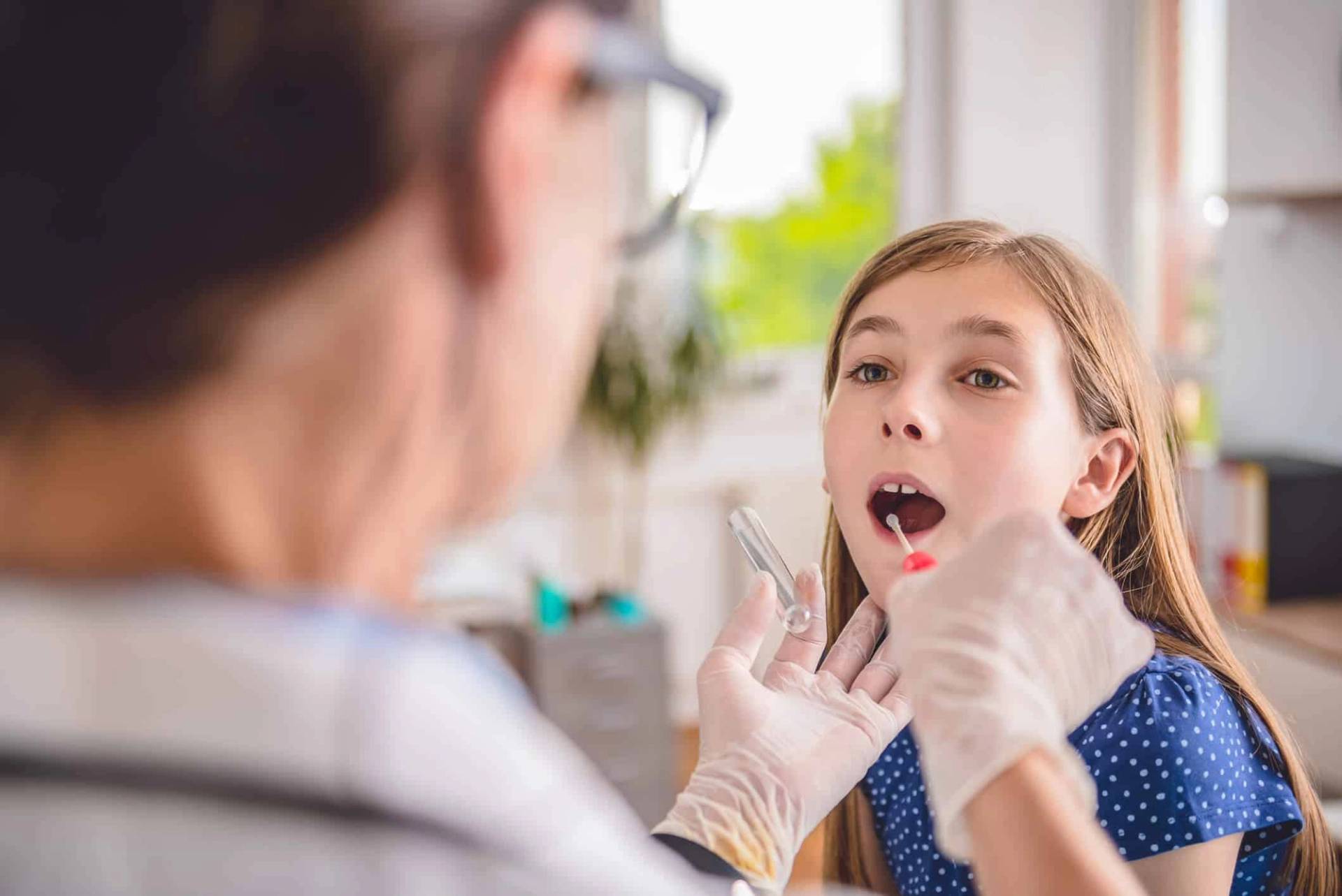Professionnelle examinant la gorge d’une enfant.