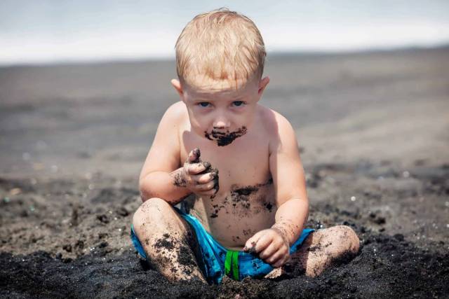 Petit enfant assis dans de la terre, avec des traces autour de la bouche.