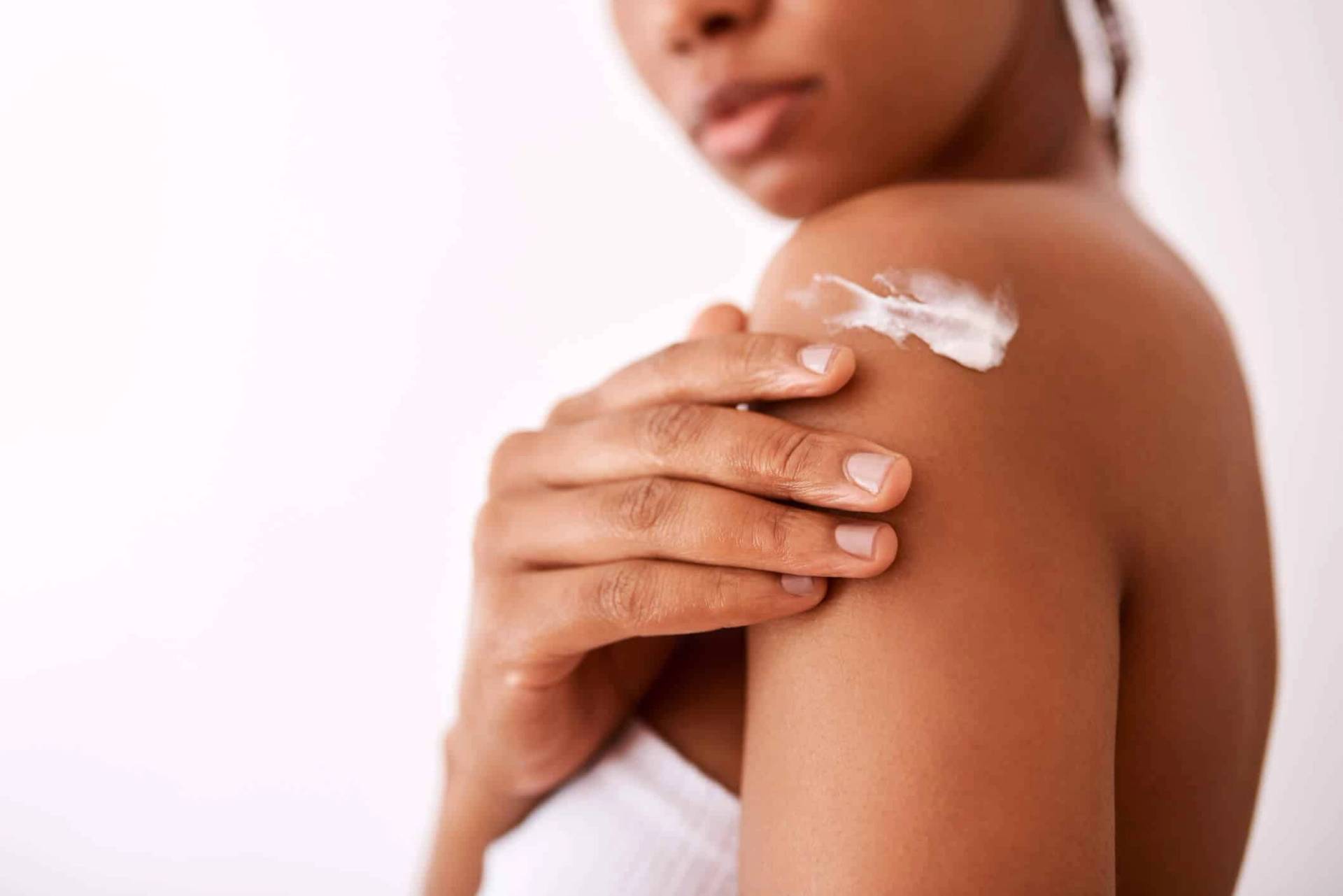 Femme appliquant une crème sur son épaule.