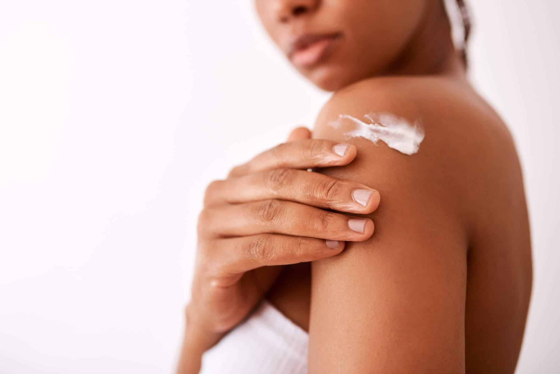 Femme appliquant une crème sur son épaule.