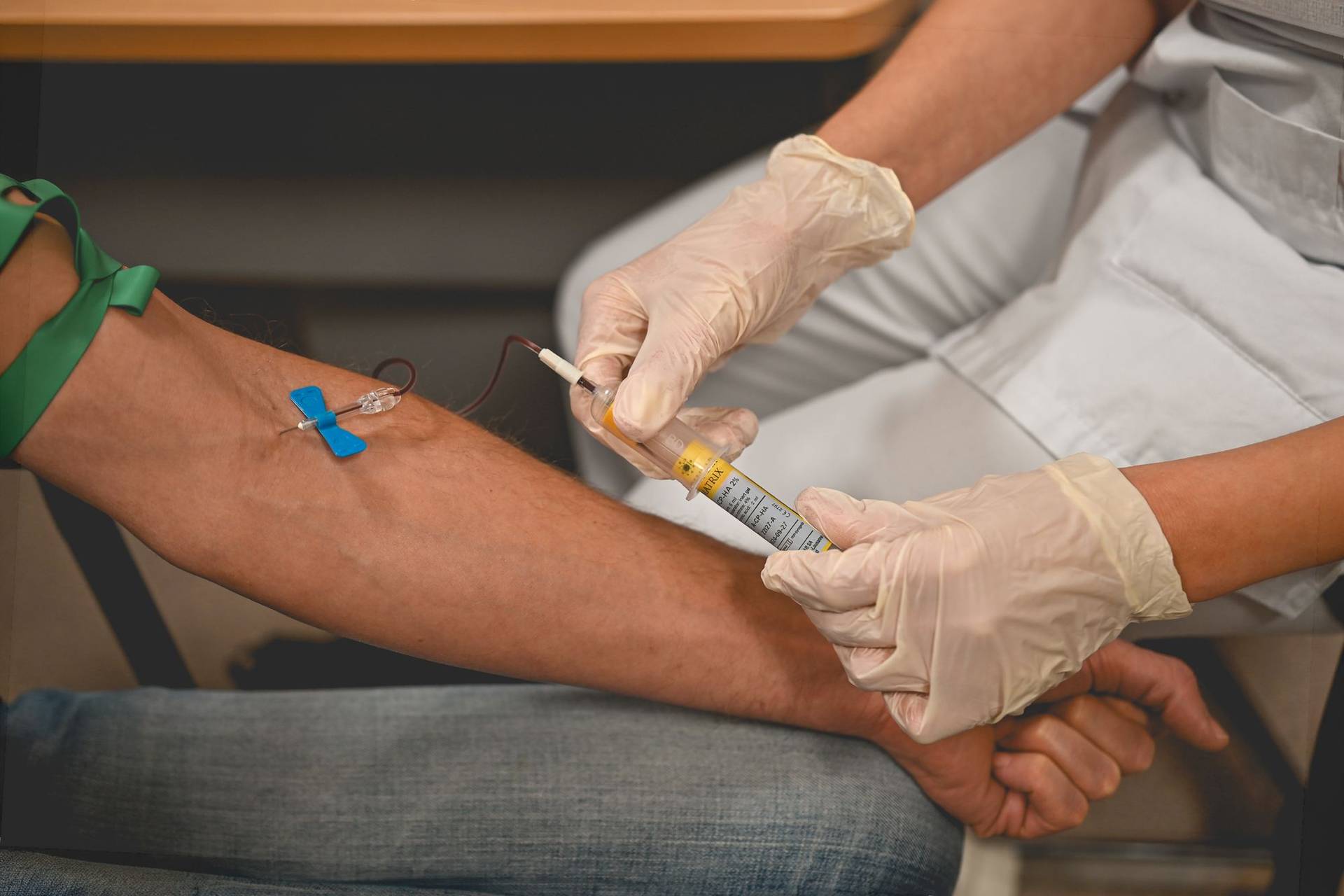 Une infirmière gantée réalise une prise de sang au pli du coude pour un dépistage des IST.