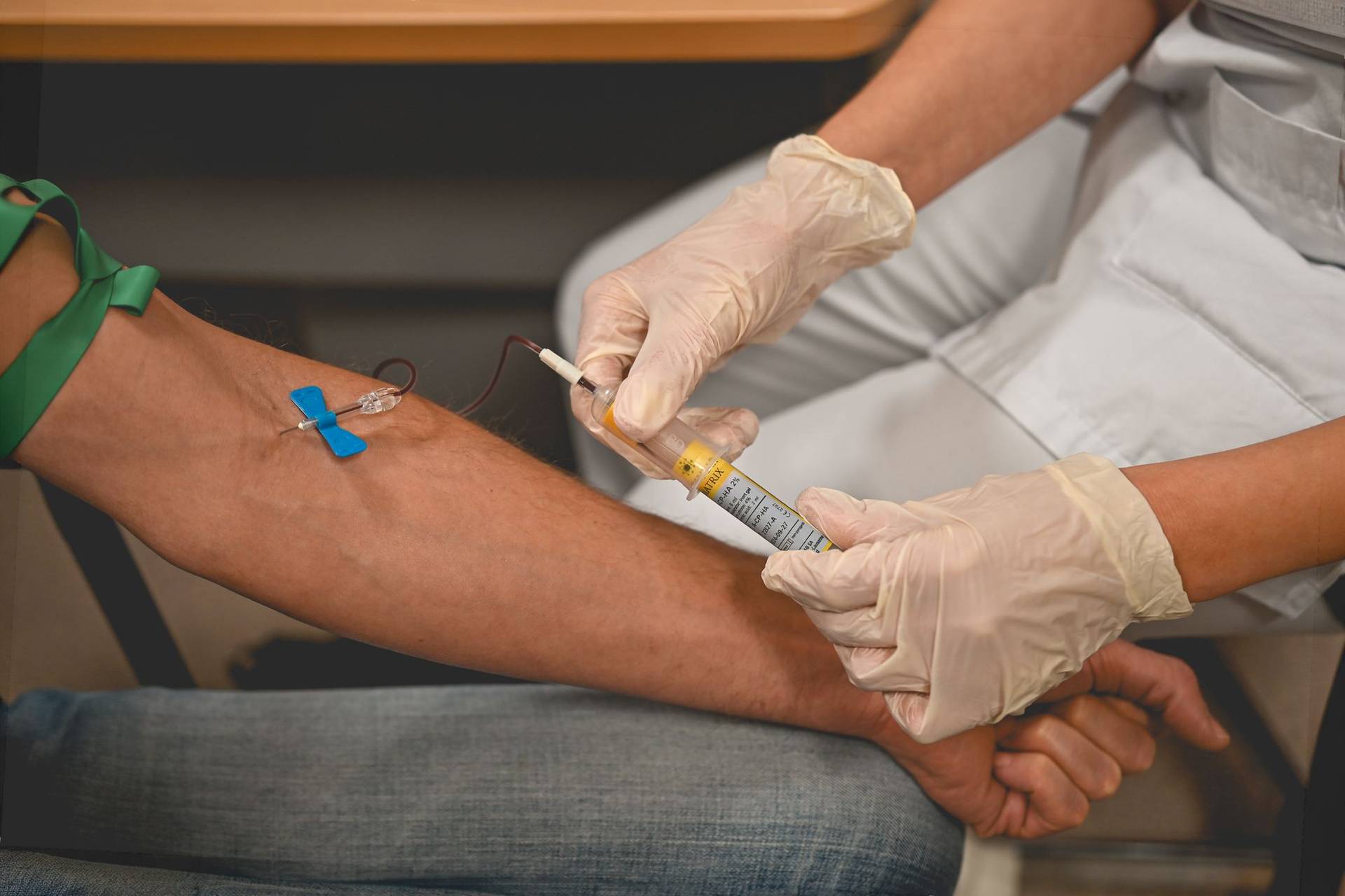 Une infirmière gantée réalise une prise de sang au pli du coude pour un dépistage des IST.