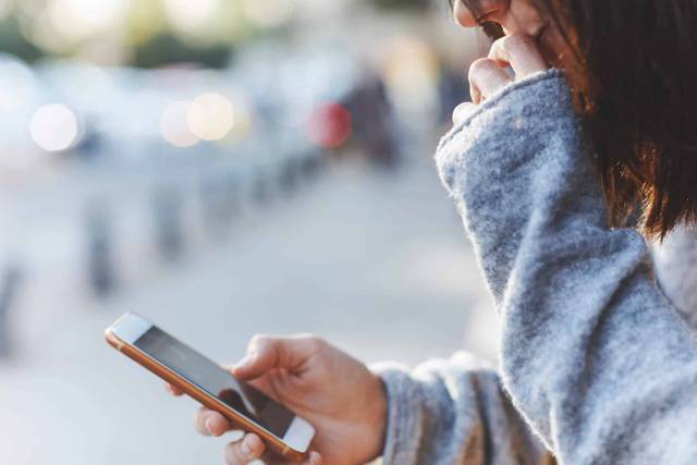 Femme consultant son téléphone dans un espace public.