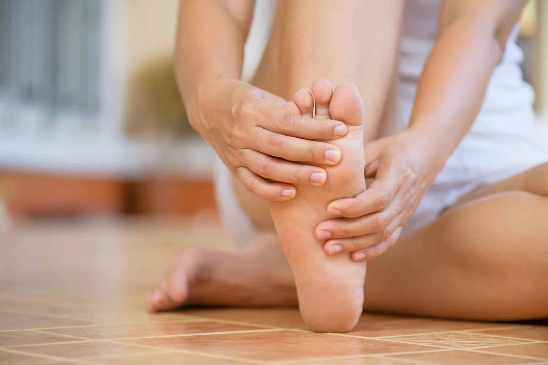 Personne tenant son pied et ses orteils dans ses mains.