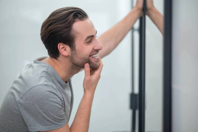 Homme souriant en regardant son reflet dans un miroir.