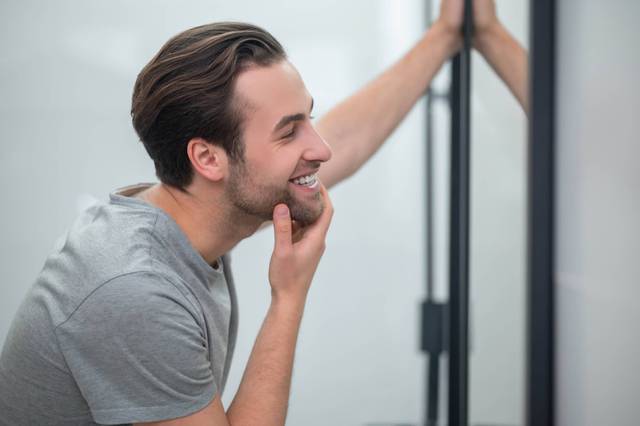 Homme souriant en regardant son reflet dans un miroir.