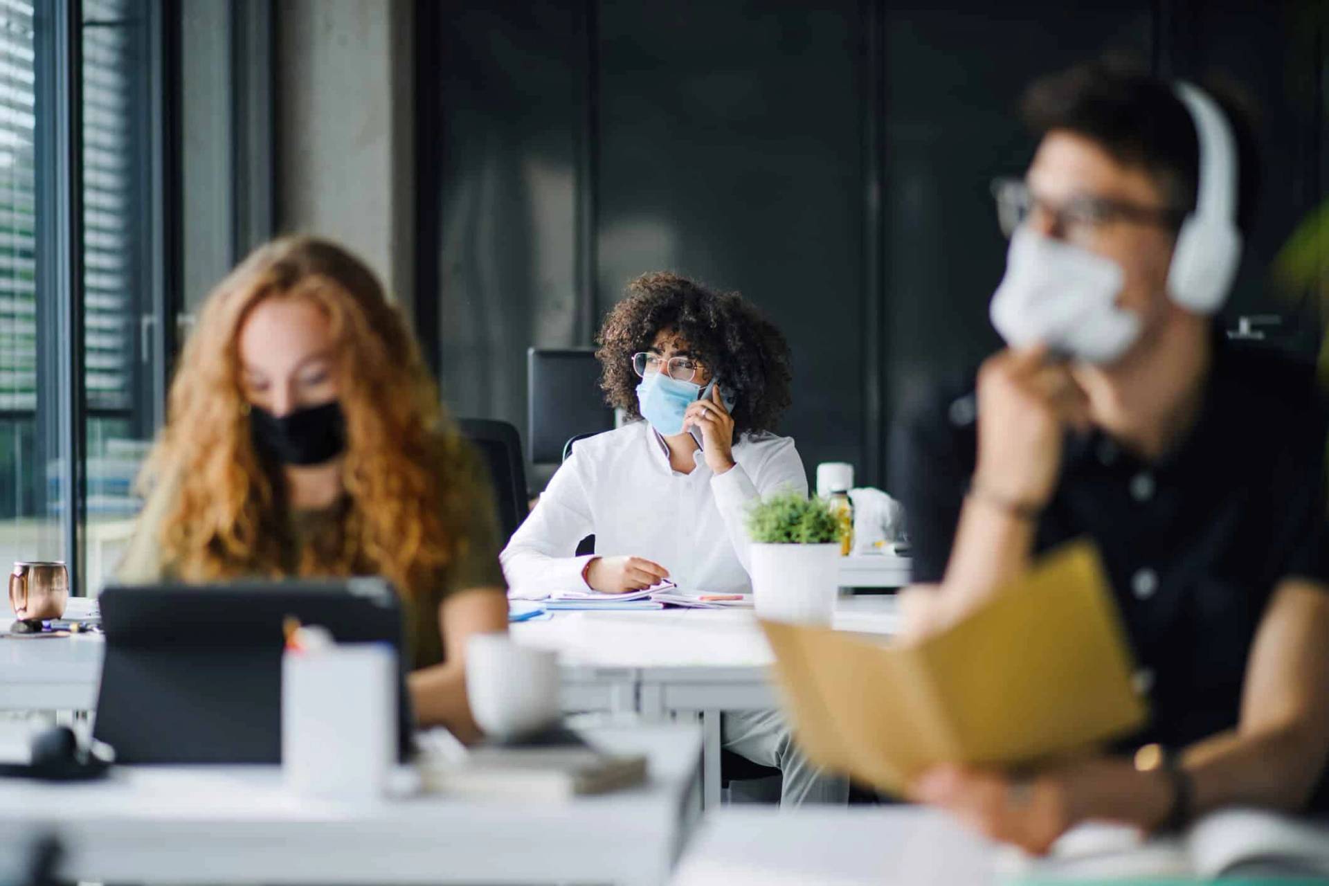 Personnes portant des masques dans une salle de travail partagée.