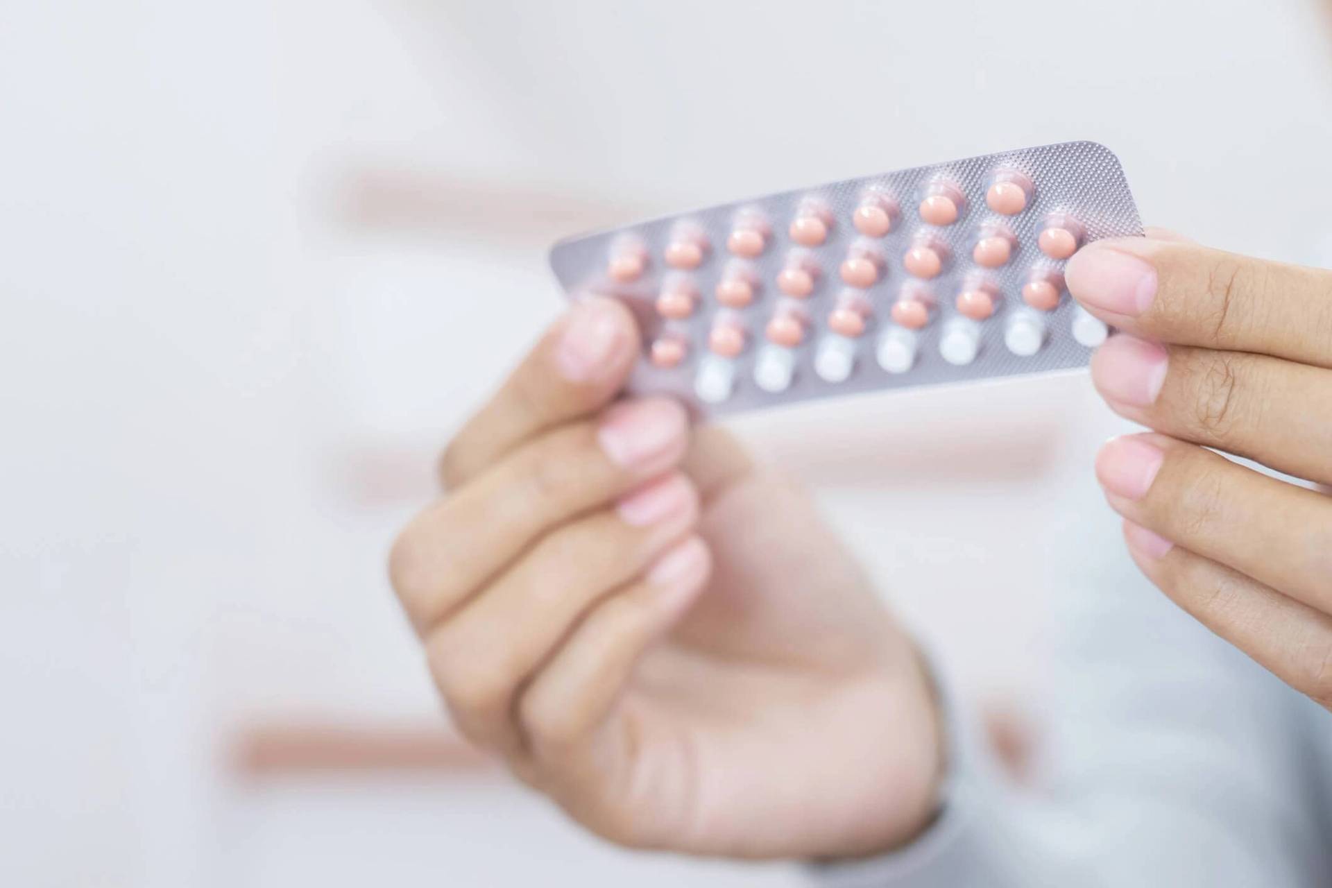 Femme devant une plaquette de pillule contraceptive