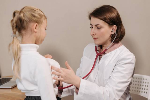 Médecin effectuant un examen de santé sur un enfant avec un stéthoscope dans un cadre clinique