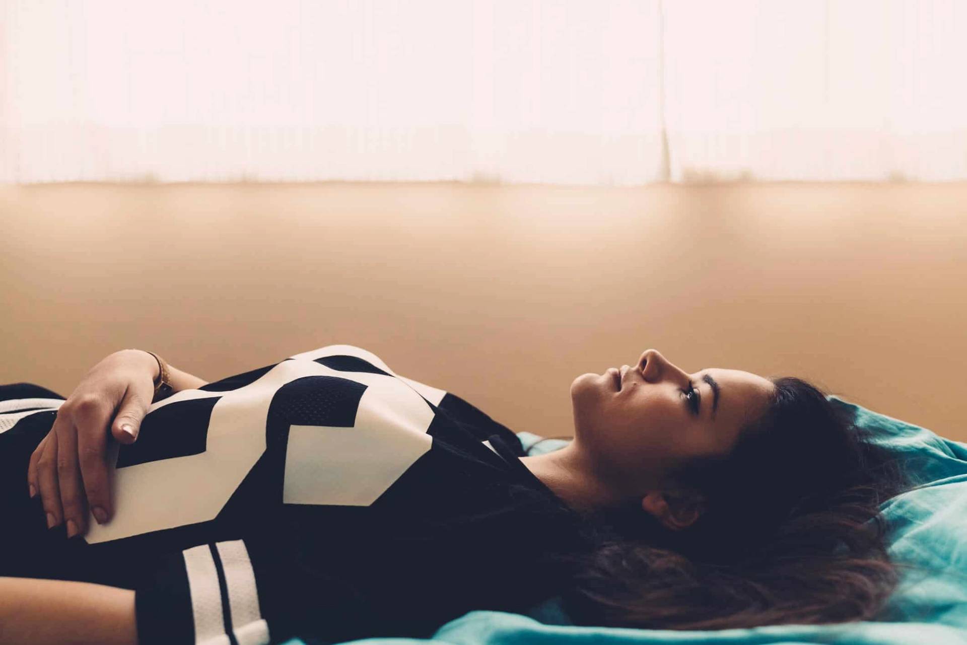Femme allongée sur un lit, les yeux ouverts.