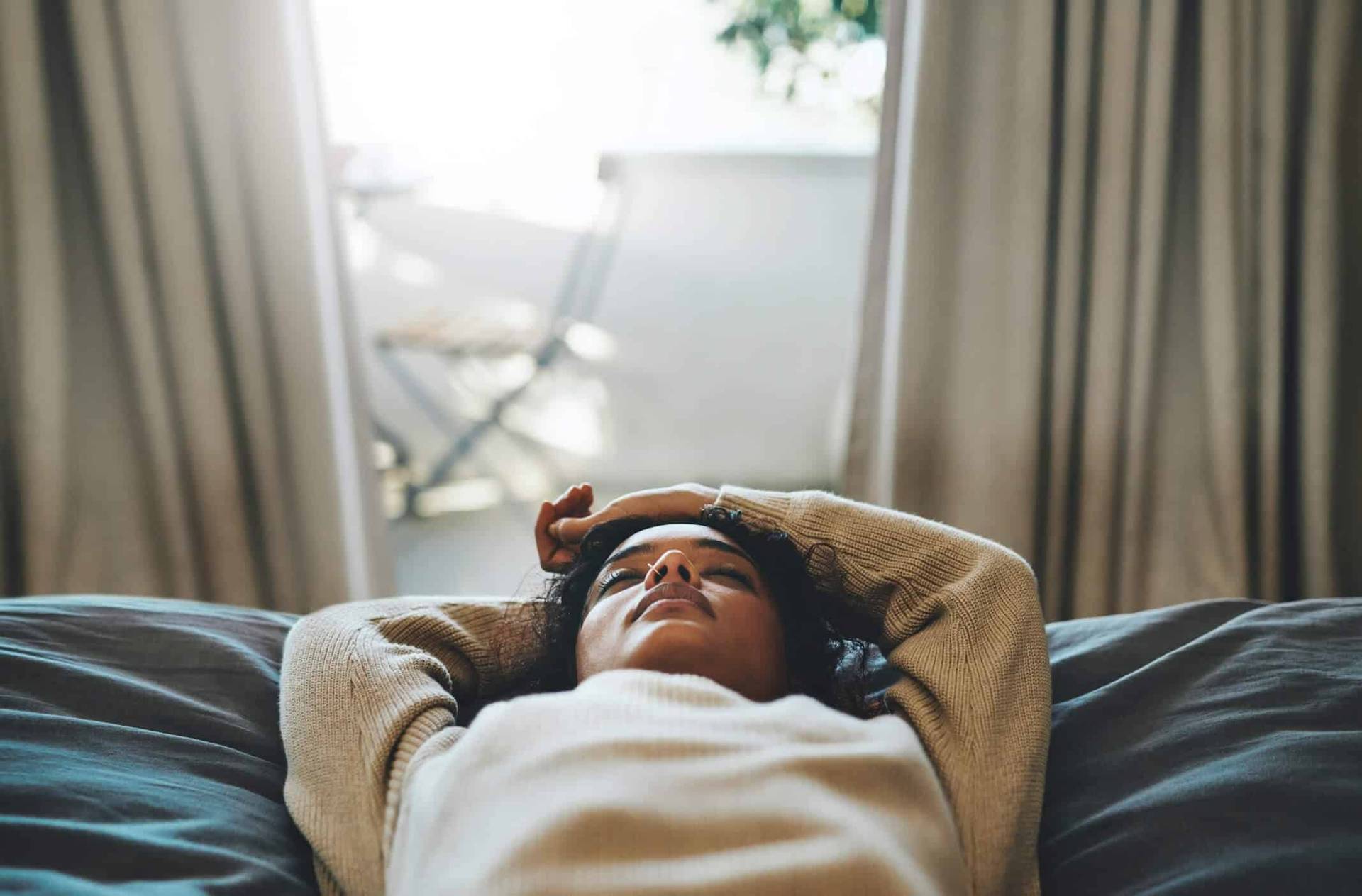 Femme allongée sur un canapé, une main sur le front.