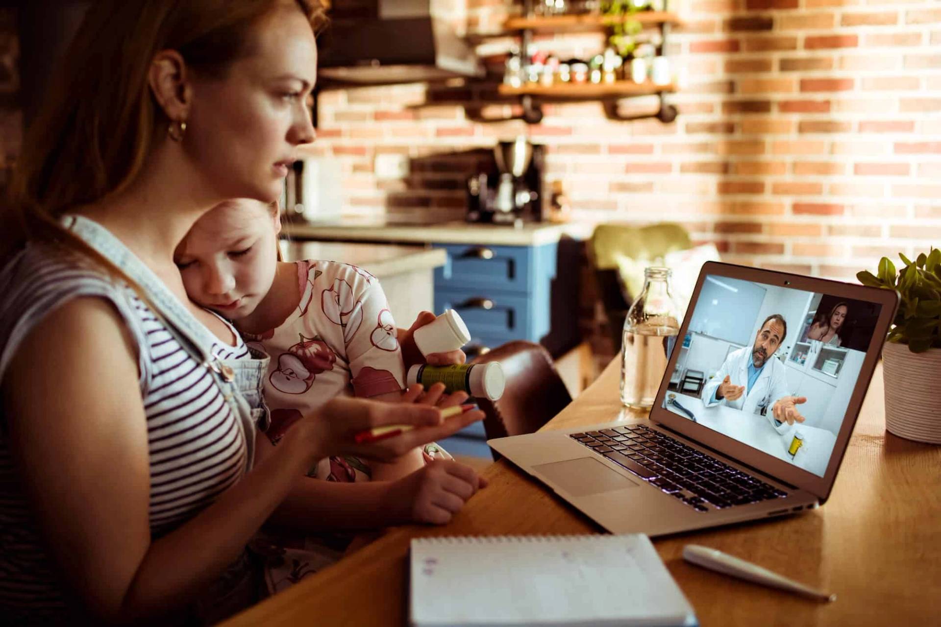 Adulte tenant un bébé pendant une consultation vidéo sur ordinateur.