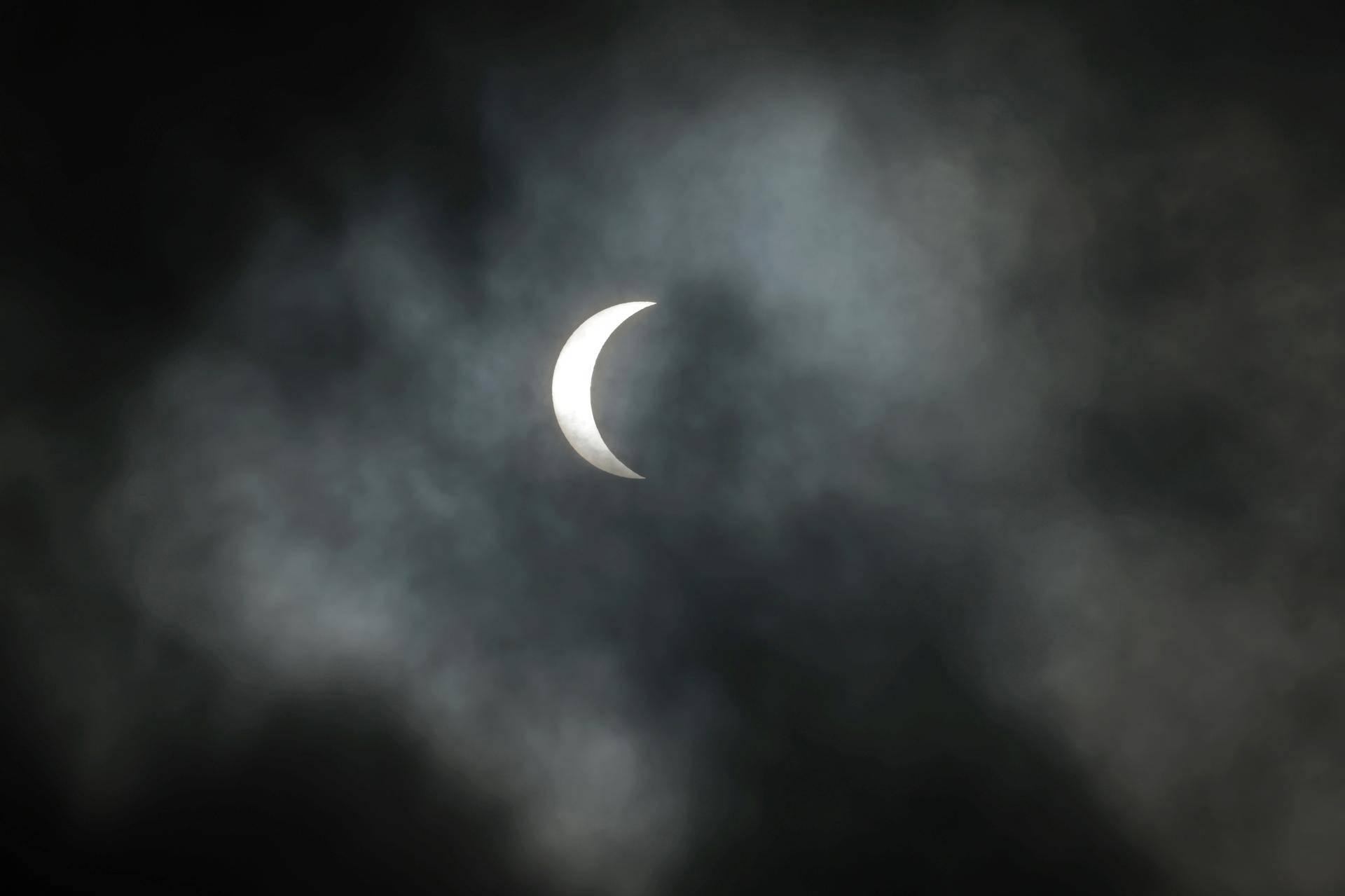Éclipse partielle visible dans un ciel nuageux.