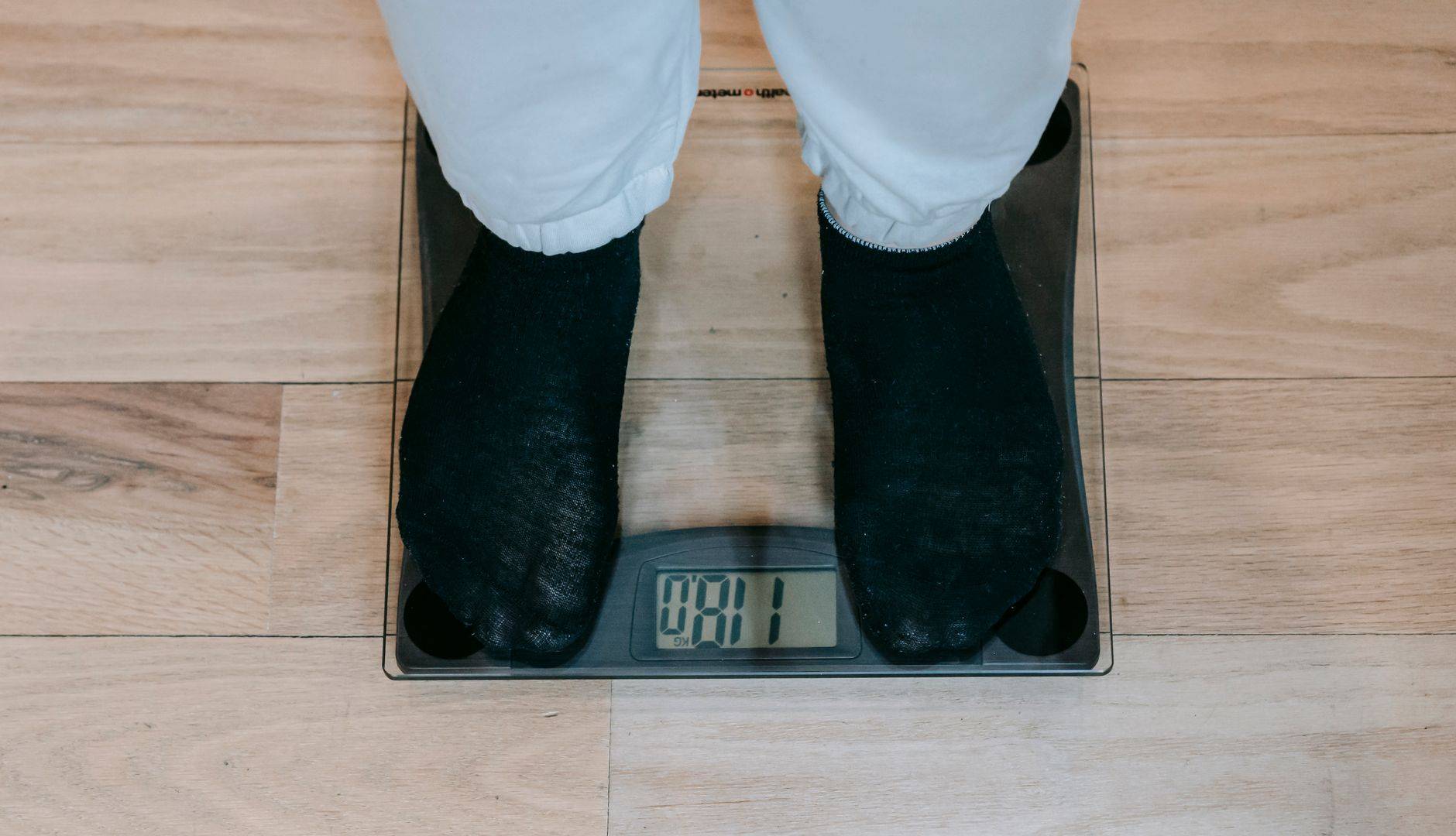 Pieds en chaussettes sur une balance électronique posée au sol.
