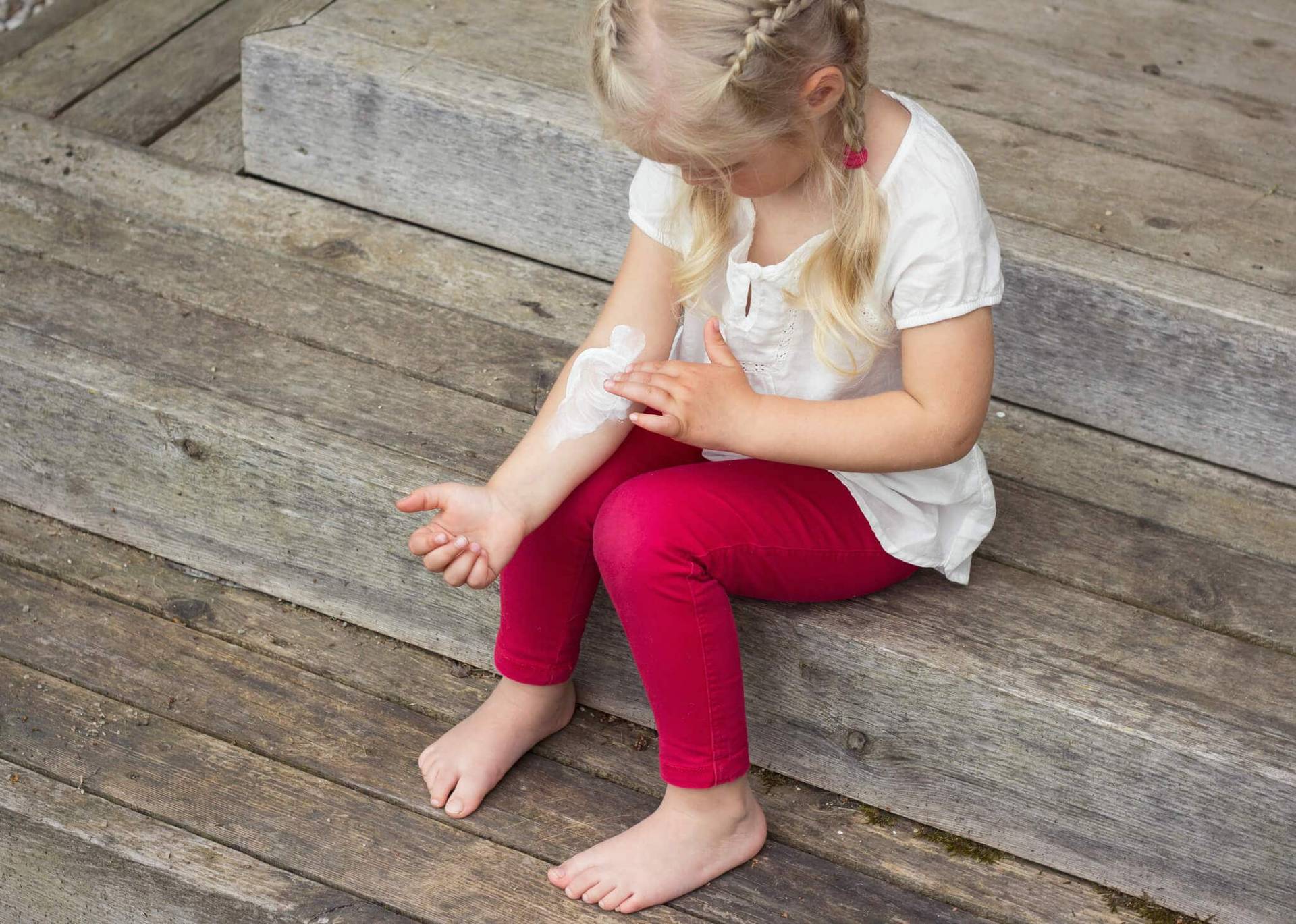 Enfant assise se grattant le bras.