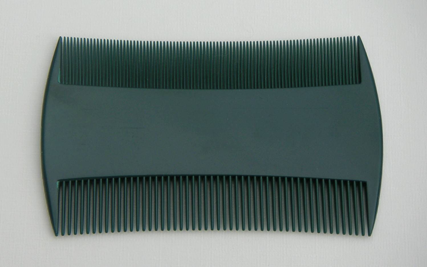 Peigne anti-poux à deux rangées de dents serrées, posé sur un fond clair.