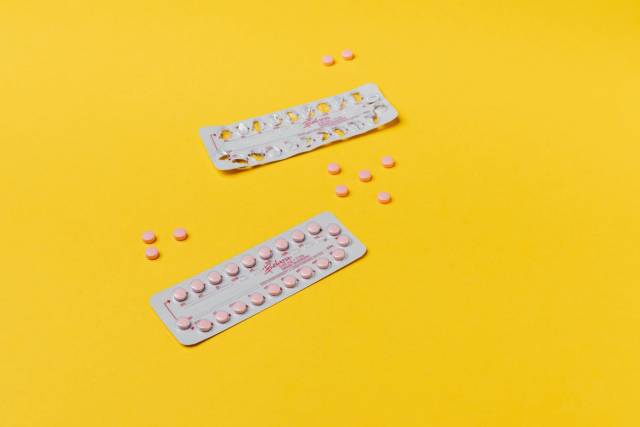 Pilules roses et plaquettes sur un fond jaune vif, symbolisant les soins de santé