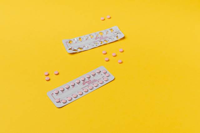 Pilules roses et plaquettes sur un fond jaune vif, symbolisant les soins de santé
