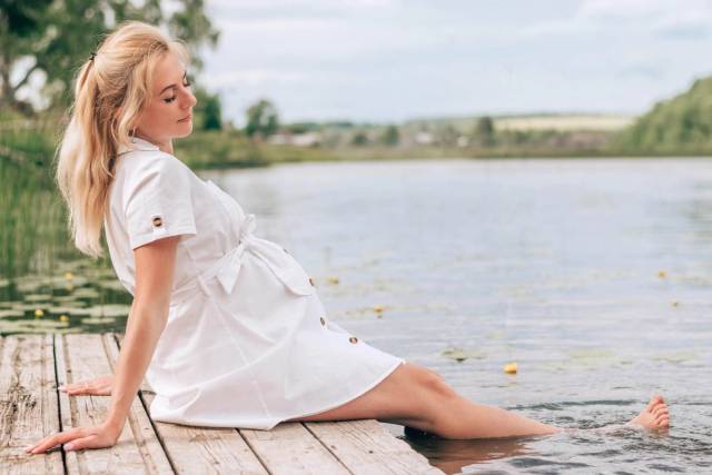 Femme au ventre arrondi assise au bord de l’eau.