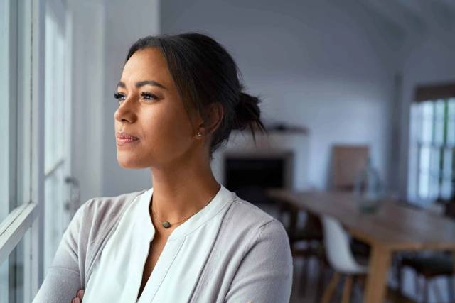 Femme près d’une fenêtre, regardant à l’extérieur.