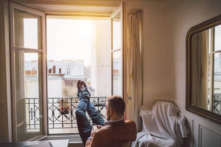 Personne assise près d’une fenêtre ouverte dans un appartement.