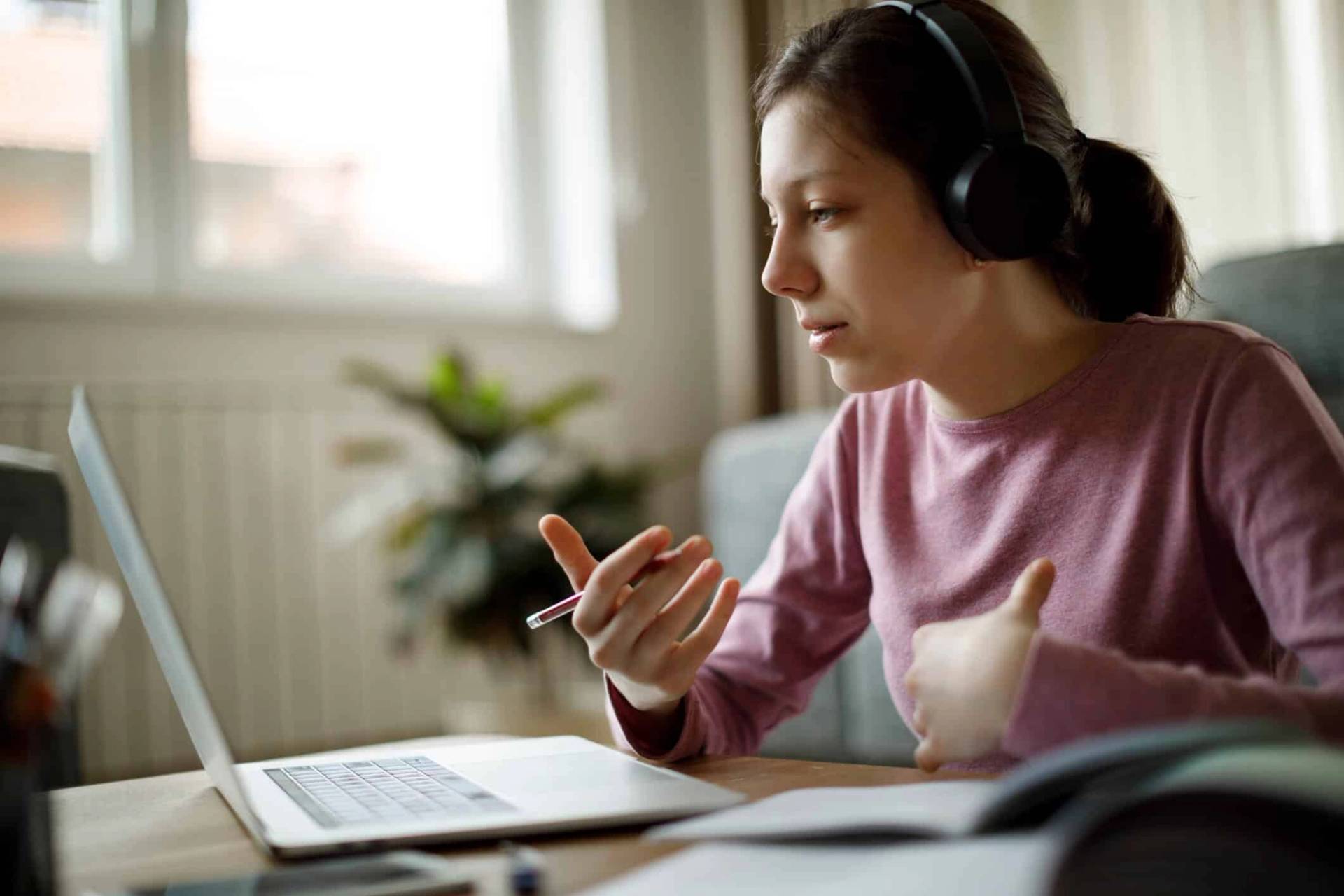 Femme portant un casque et échangeant devant son ordinateur portable.