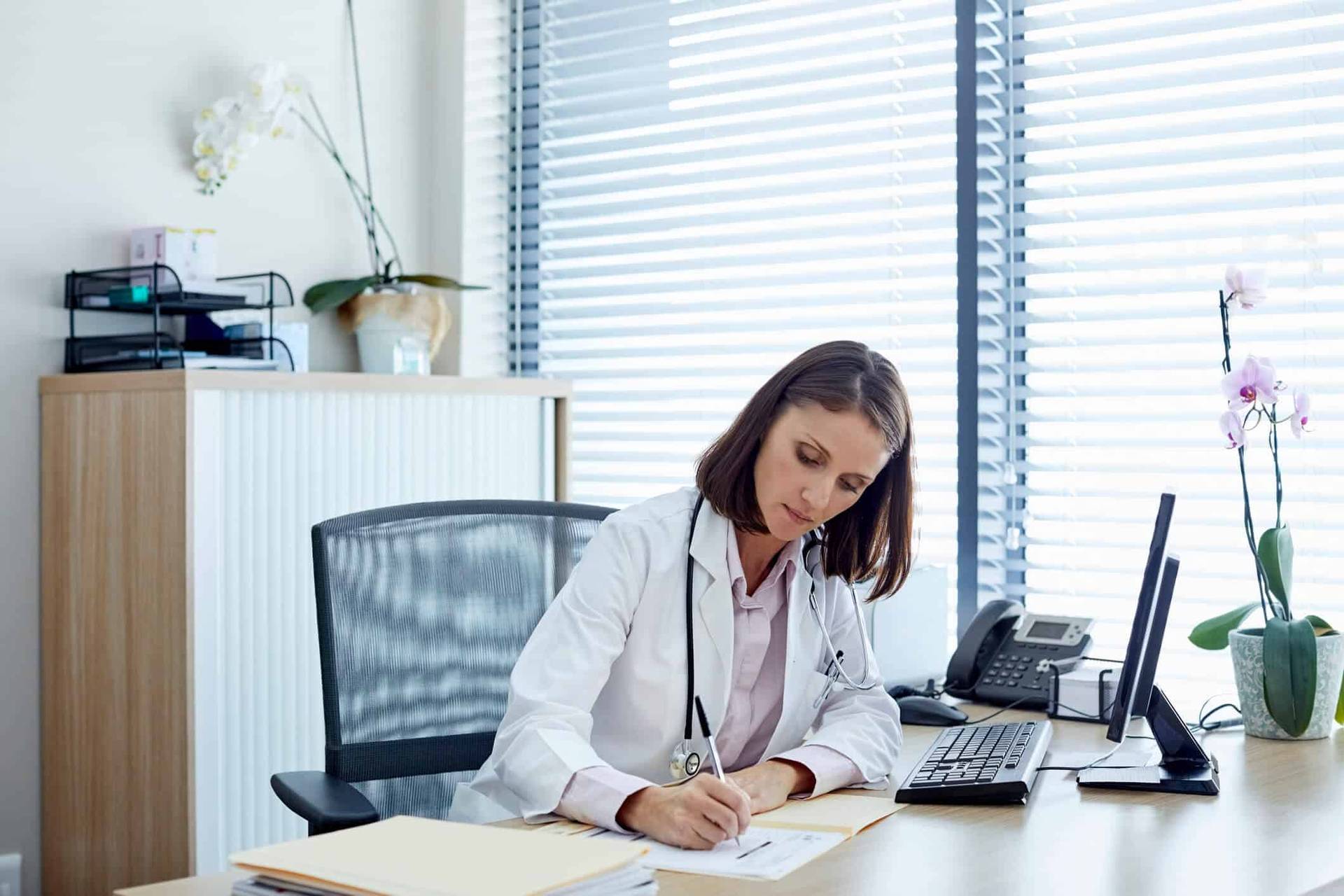 Professionnelle en blouse écrivant à un bureau.