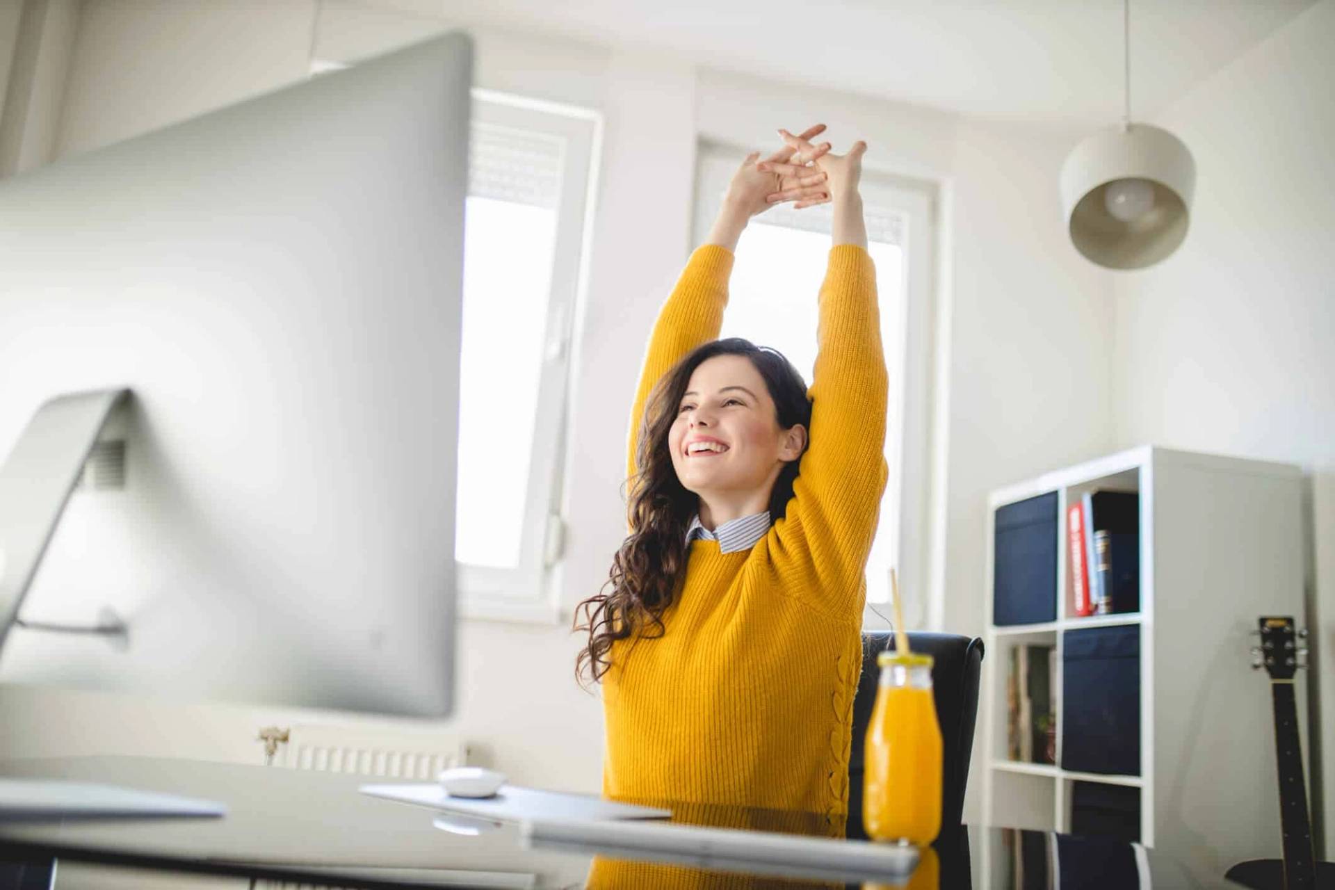 Femme s’étirant devant un ordinateur.
