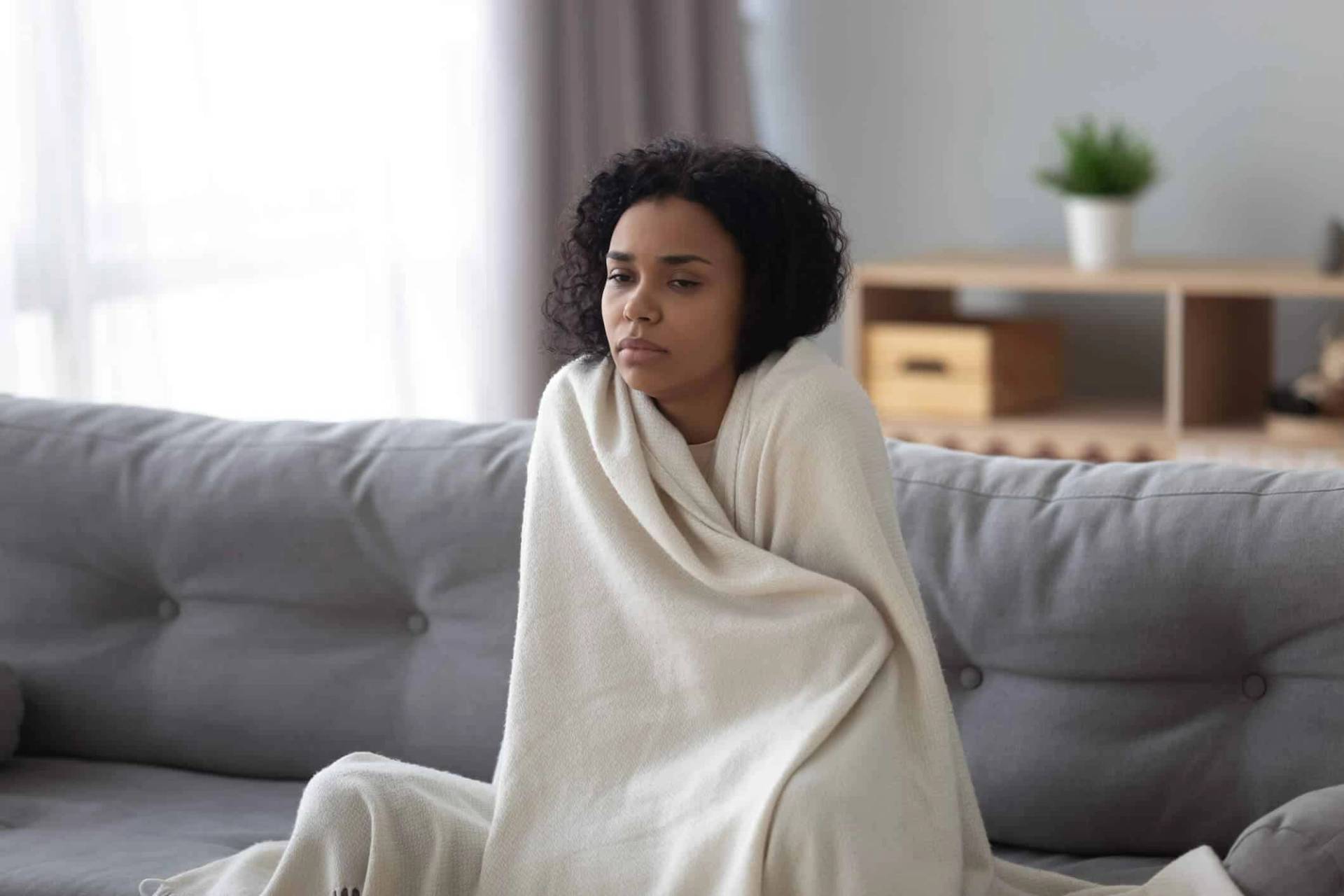 Femme enveloppée dans une couverture sur un canapé.