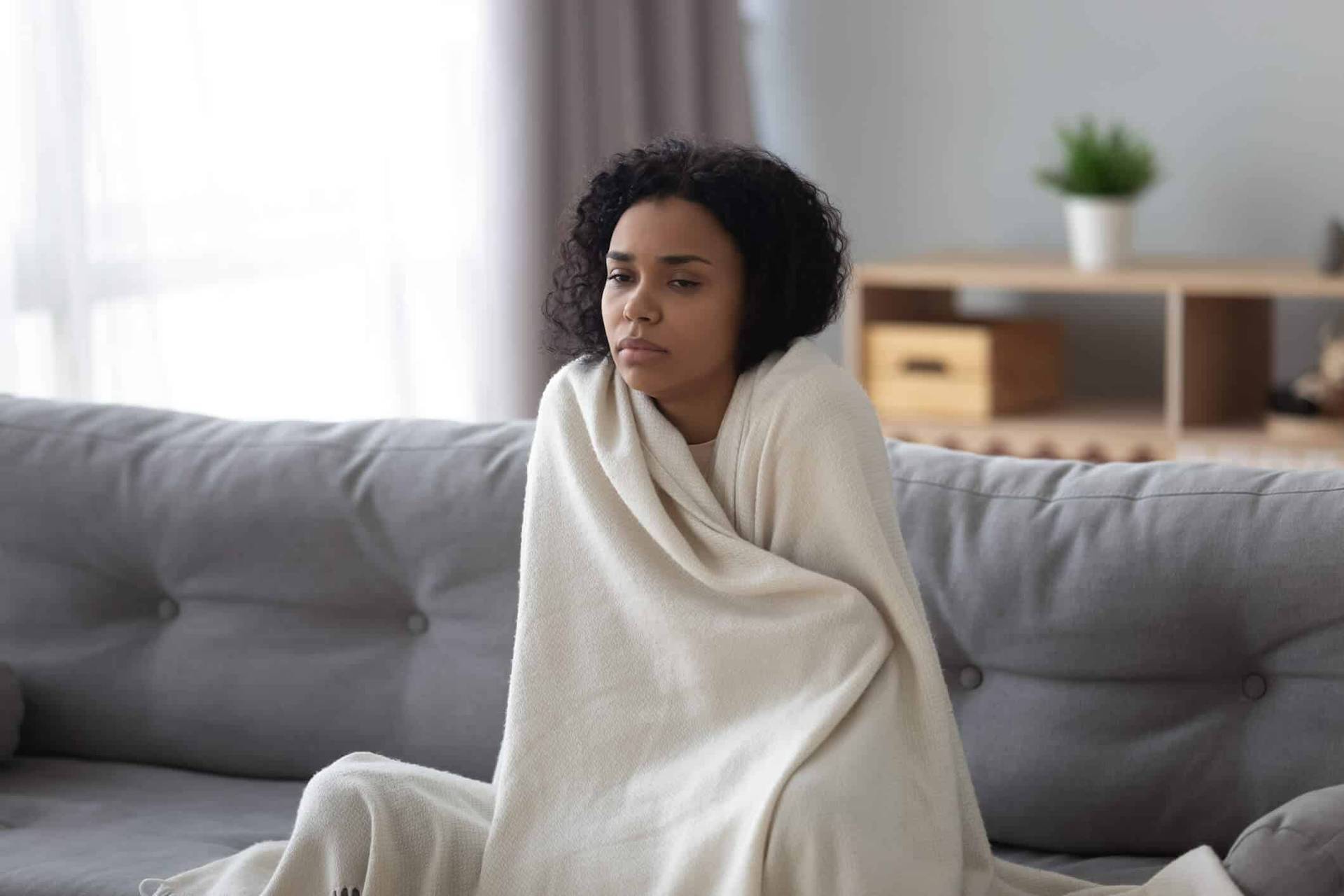 Femme enveloppée dans une couverture sur un canapé.