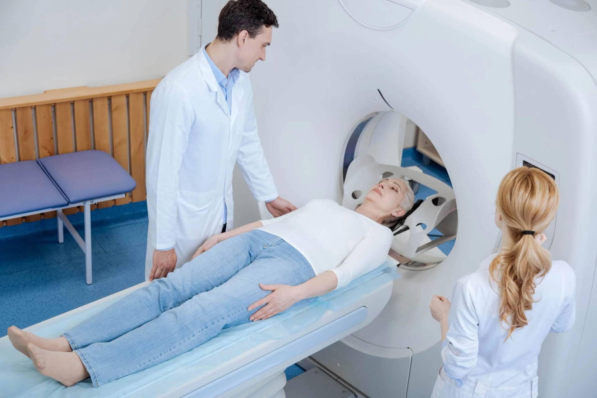 Personne allongée dans un appareil d’imagerie médicale, entourée d’autres personnes.