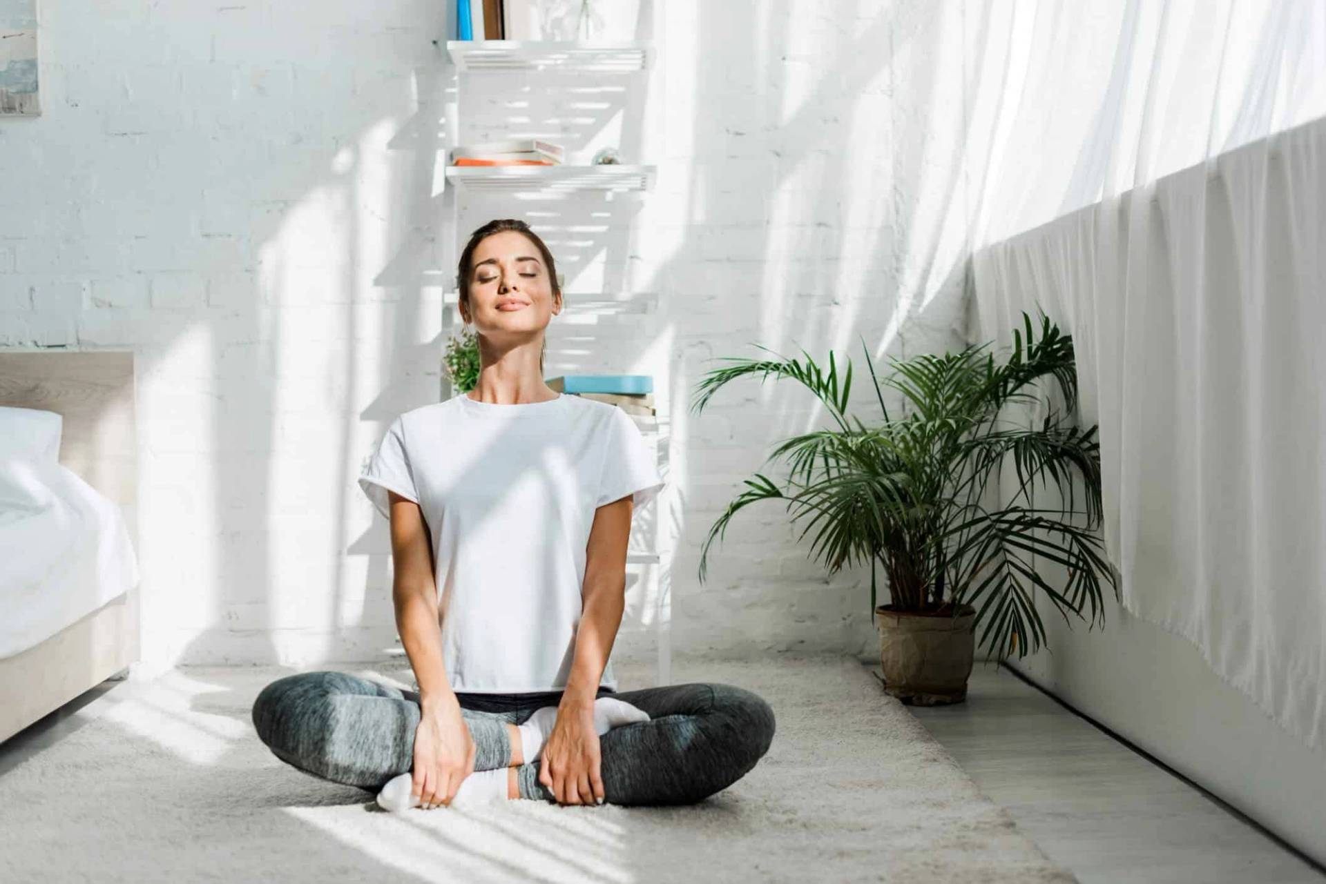 Femme assise en tailleur, les mains sur les genoux.