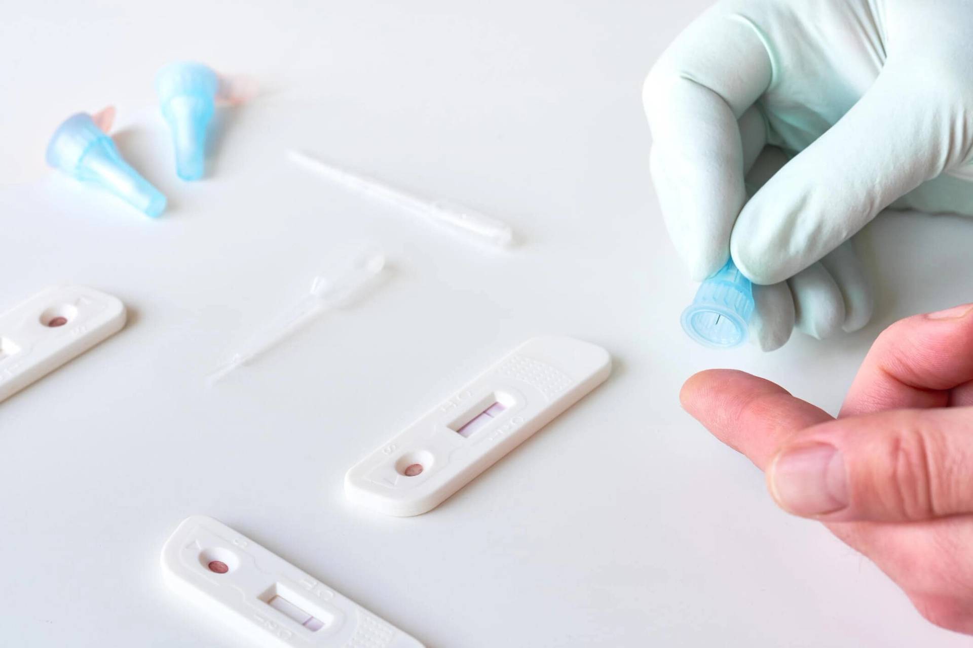 Prélèvement d’une goutte de sang au doigt près de tests rapides.