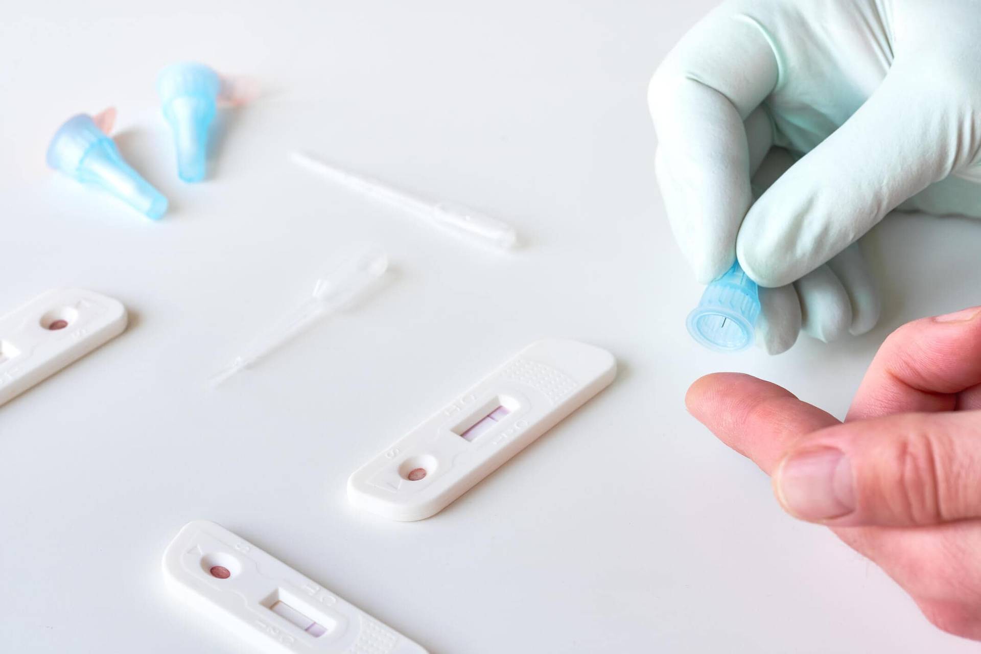 Prélèvement d’une goutte de sang au doigt près de tests rapides.