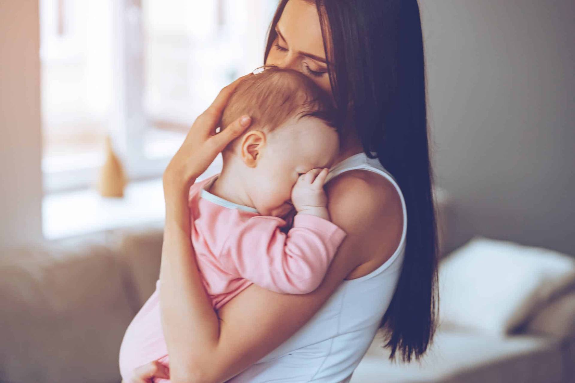 Femme tenant un bébé contre son épaule.