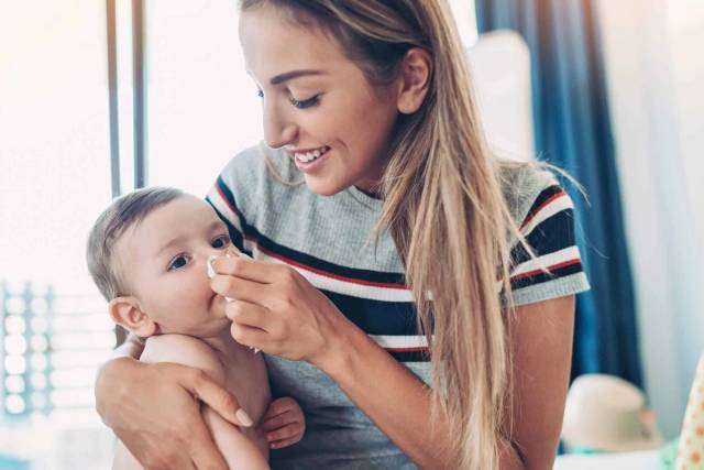 Adulte tenant un bébé et un dispositif de soin du nez.