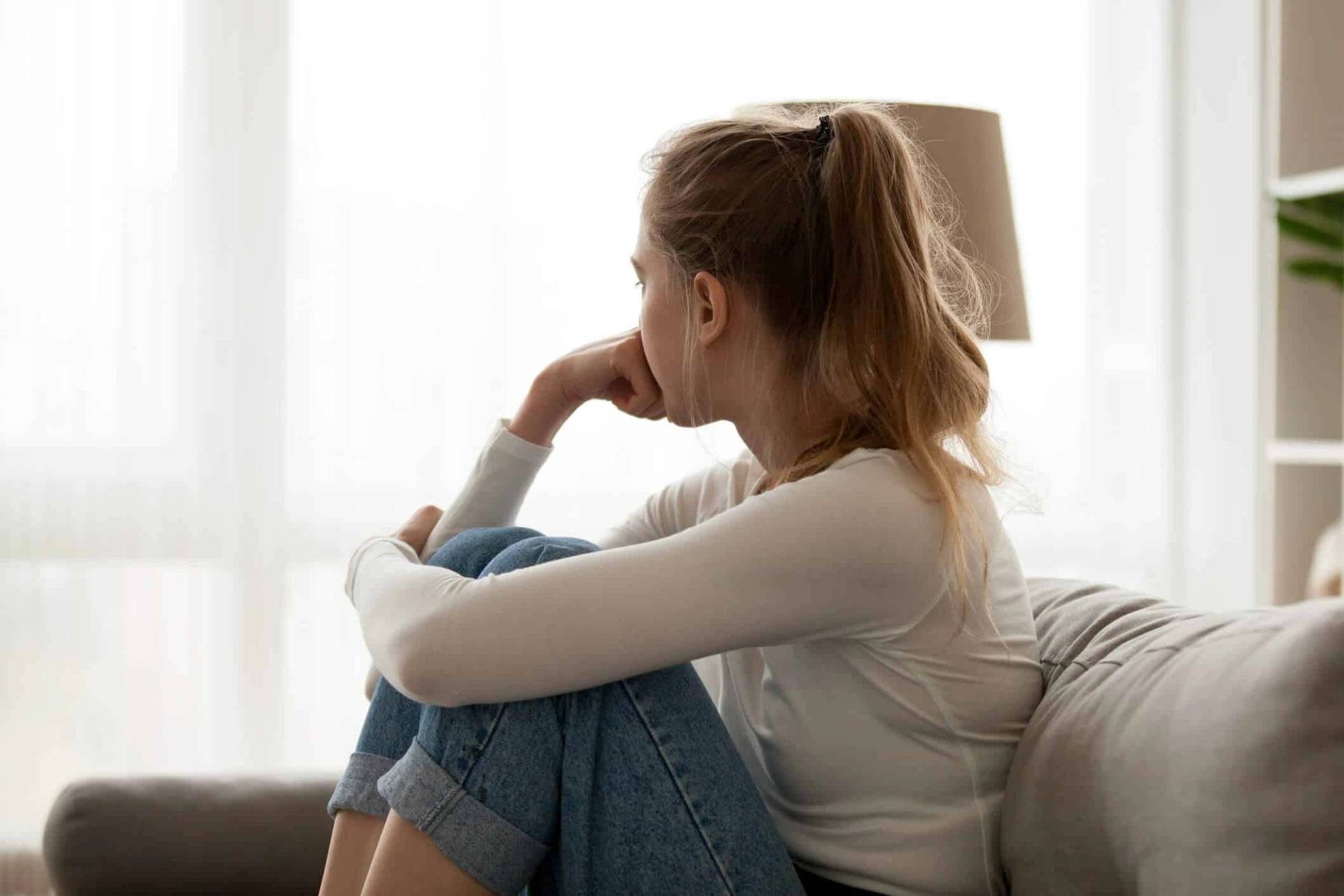 Femme assise sur un canapé, le menton posé sur une main.