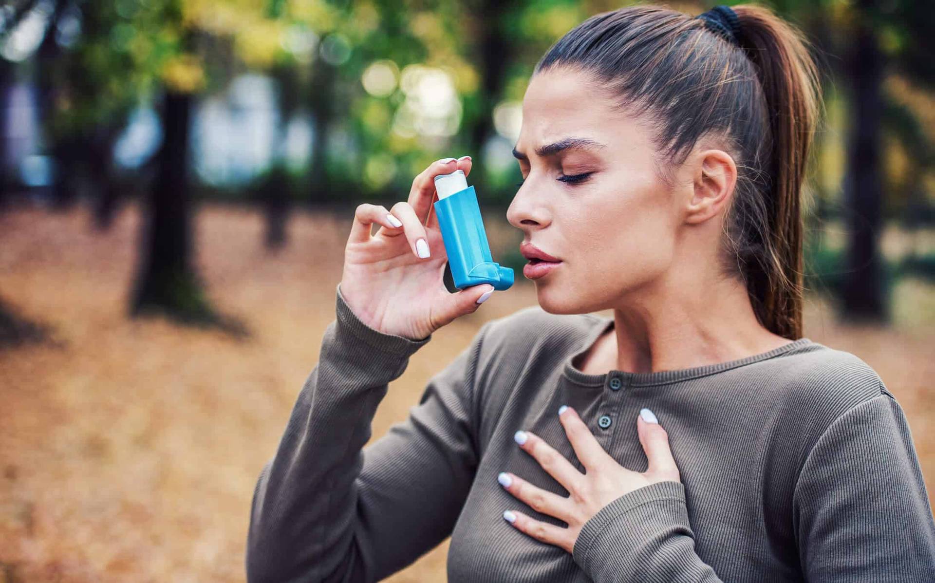 Femme utilisant un inhalateur à l’extérieur.