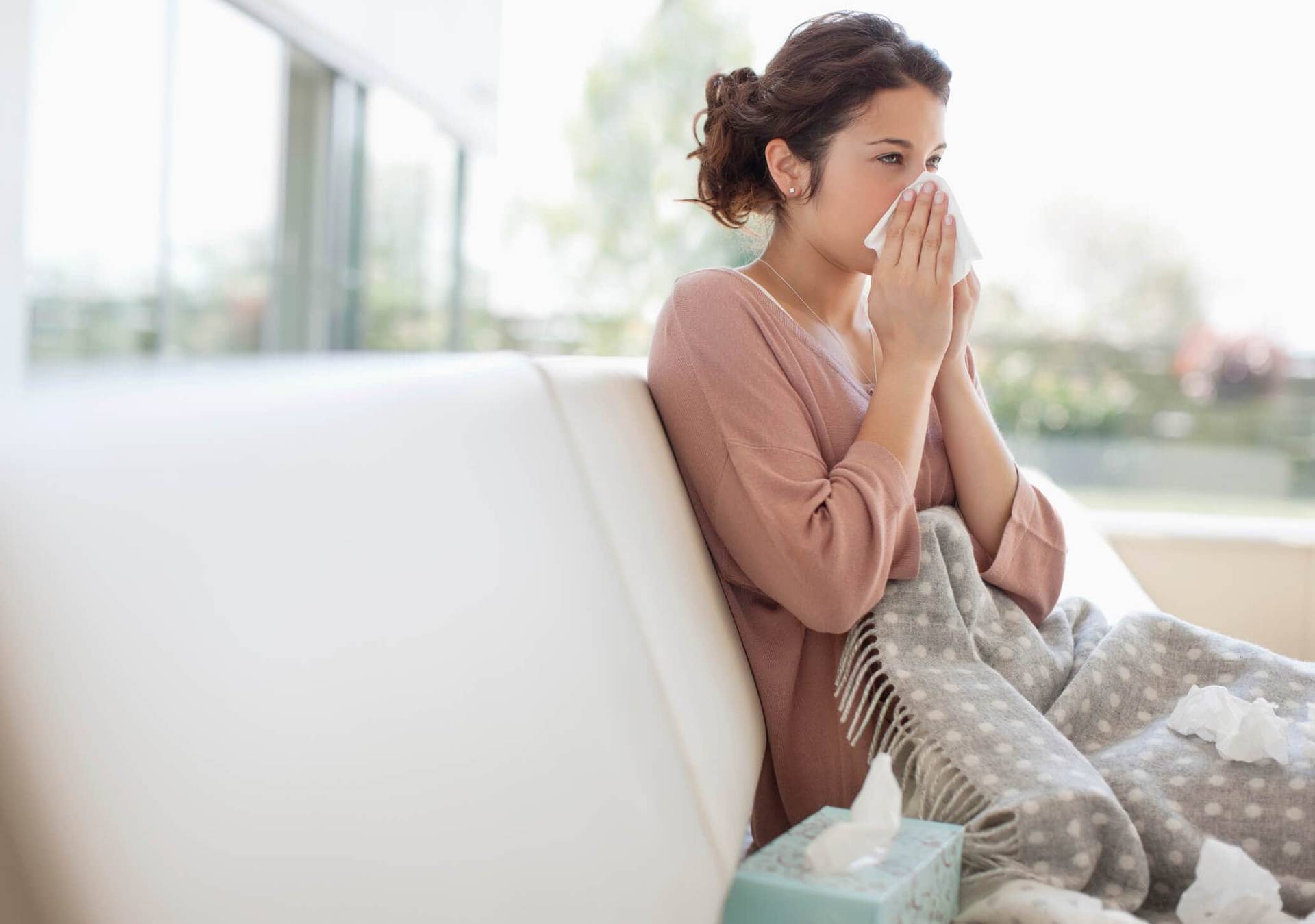 Femme enveloppée dans une couverture, tenant un mouchoir au nez.