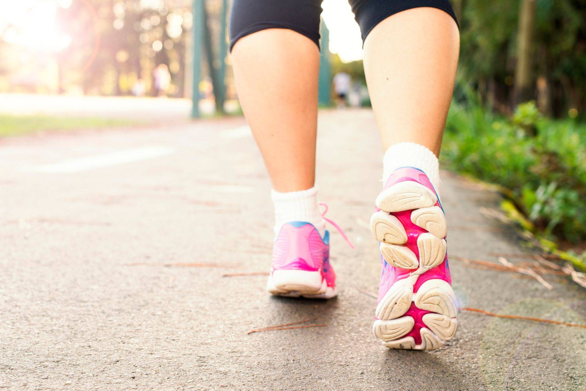 Jambes et chaussures de sport d’une personne marchant sur un chemin.